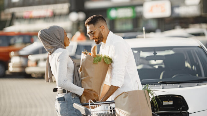 Multi ethnic couple charge elctric car after shopping