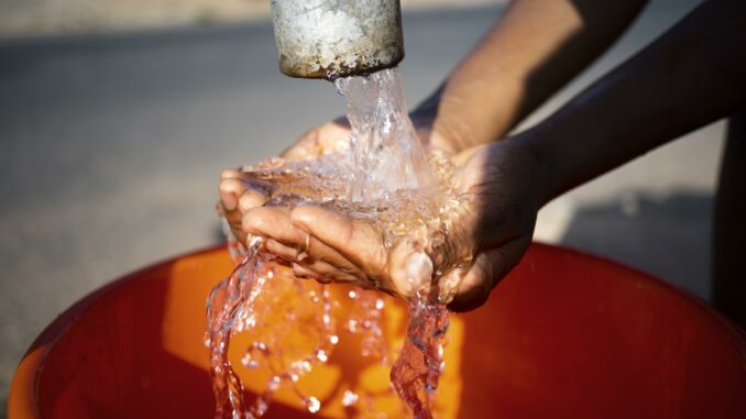 african-woman-pouring-water-recipient-outdoors