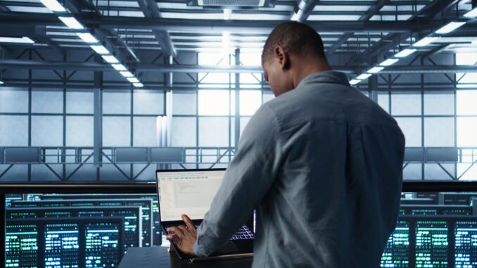 Man coding on data center, testing failover scenarios using notebook
